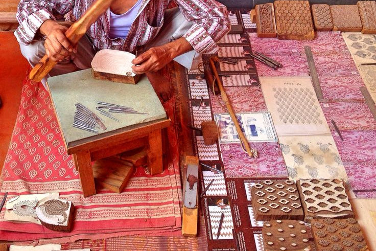 Man working with traditional printing blocks on a tablecloth with patterns