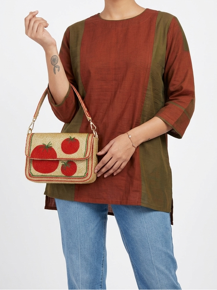 Woman holding a beaded handbag with tomato design against a white background