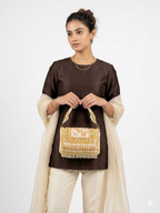 Woman holding a beige and mint beaded handbag with patterns against a white background